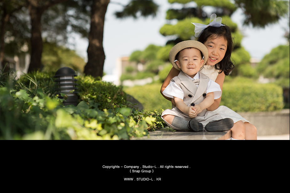 도심 공원 벤치에서 쭈그려 앉은 누나와 동생을 지켜보는 부모