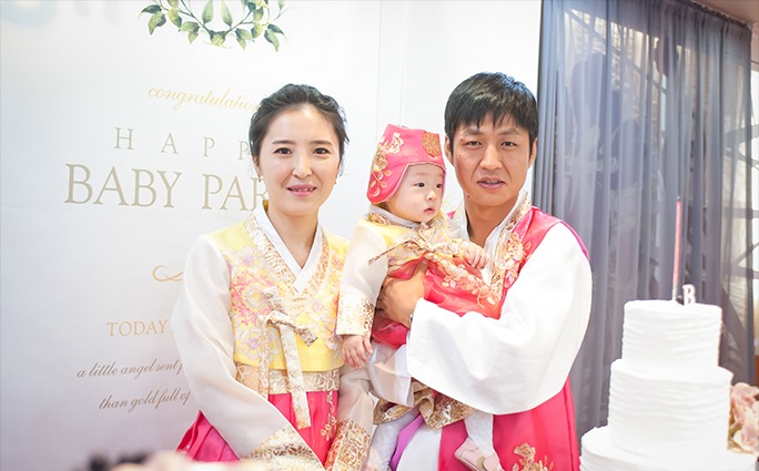 돌잔치홀 한복 가족 컷 — 복건 쓴 수민이와 한복 차림 엄마 아빠