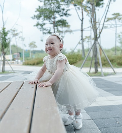 야외 테이블에 기댄 예빈이 단독 — 옆을 바라보며 미소